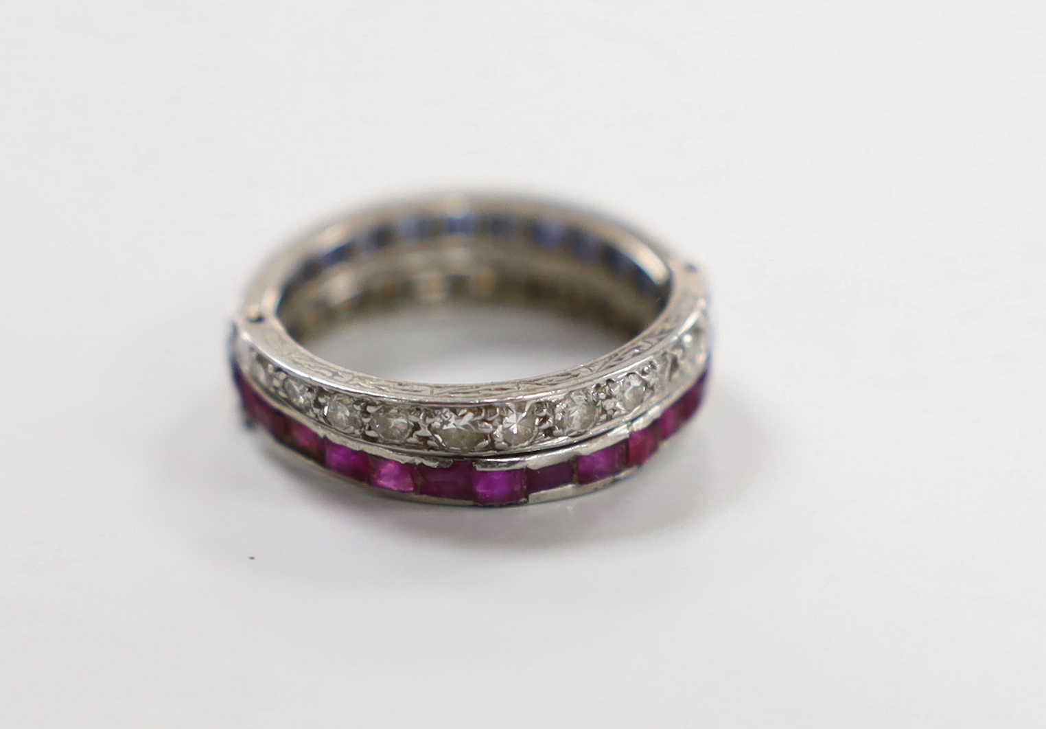 A white metal, sapphire, ruby and diamond set triple band swivel ring, size L, gross weight 4.4 grams (a.f.).